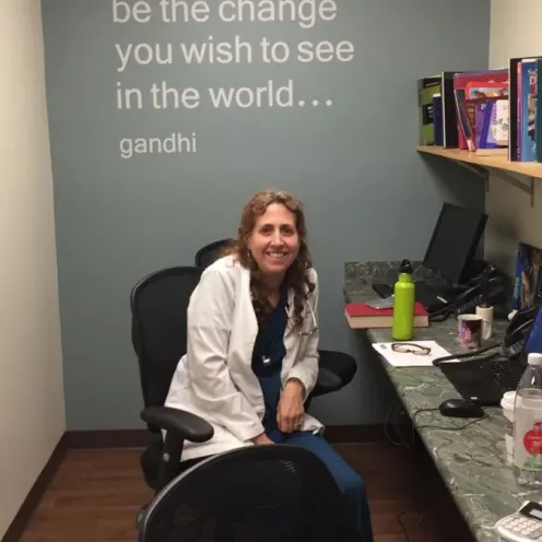 Veterinarian sitting at a row of computers, in front of a wall with a quote on it
